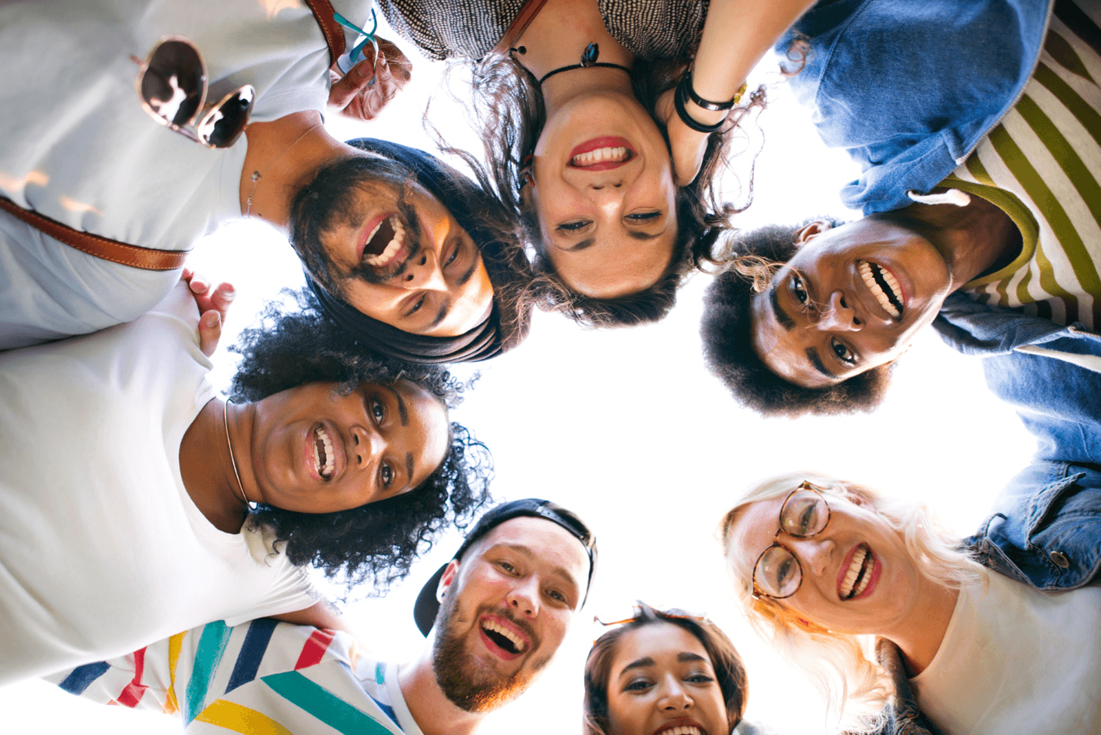 A diverse group of smiling people looking down toward the camera in a circle.