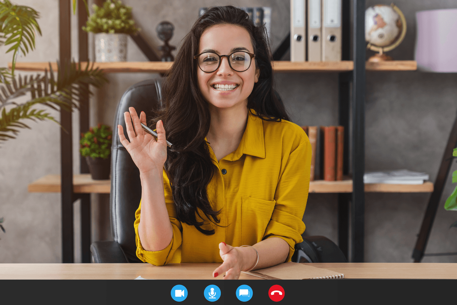 A smiling woman on a video call at her desk.